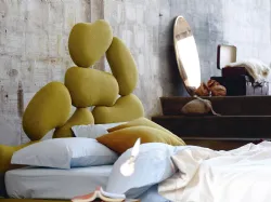 Double bed with wooden headboard cut with a pantograph and upholstered with soft rubber.