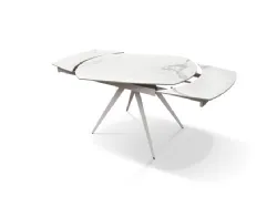 Extendable shaped table with ceramic top and central metal base in white finish.
